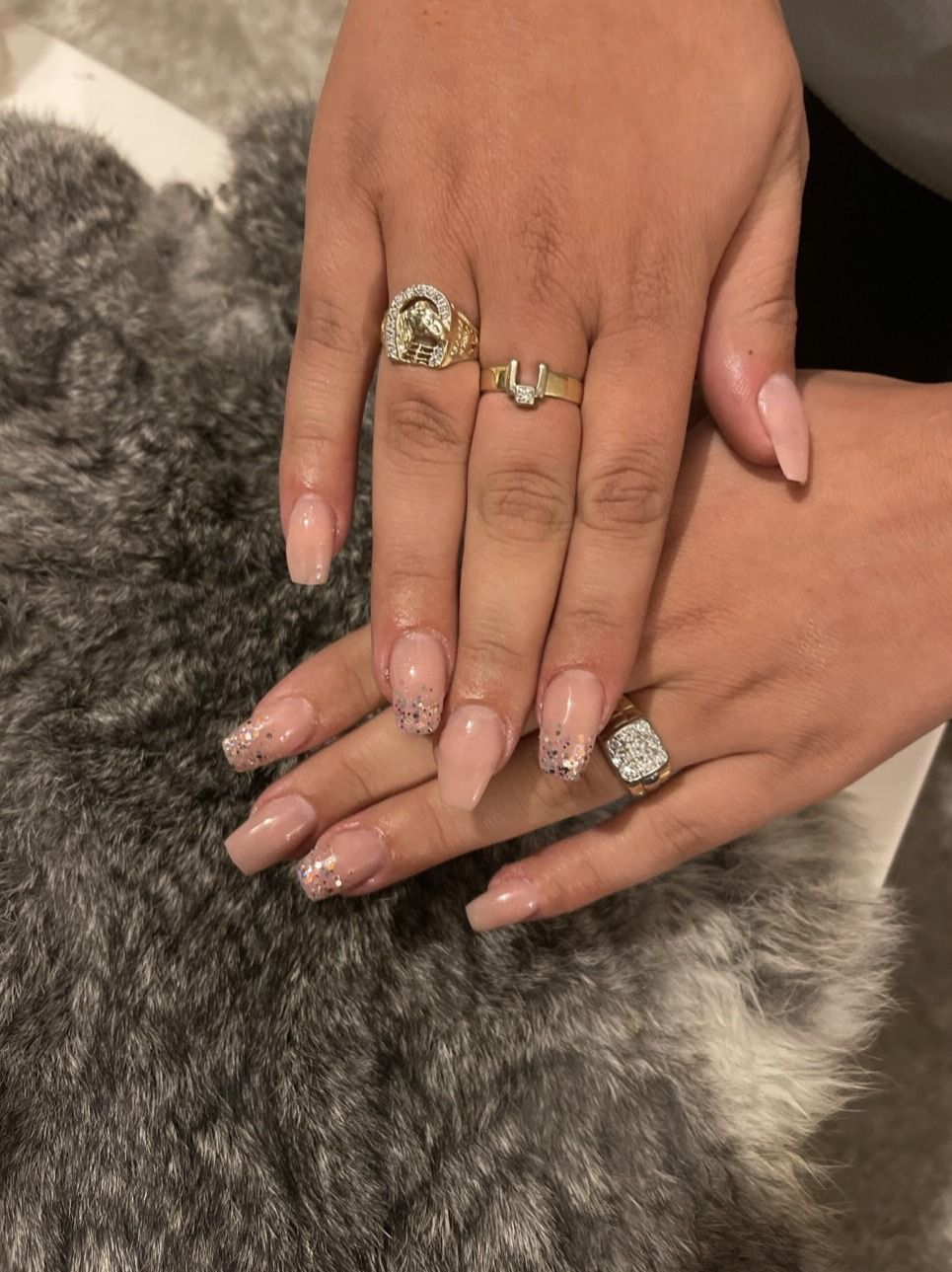 Lange nude nagels met glitter in de punt, op een grijze bontdeken